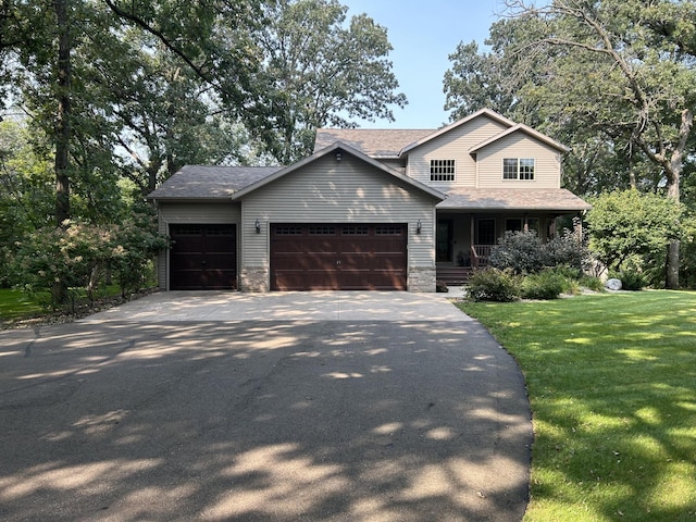 view of front of home featuring covered porch, a garage, and a front yard