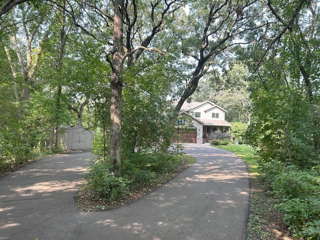 view of property hidden behind natural elements featuring a storage unit