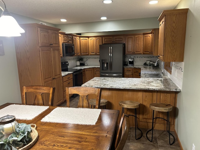 kitchen featuring sink, kitchen peninsula, decorative backsplash, a breakfast bar, and black appliances