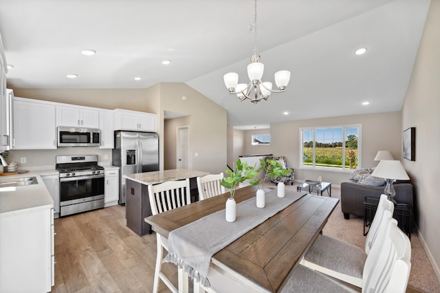 dining area with lofted ceiling, a chandelier, light hardwood / wood-style floors, and sink