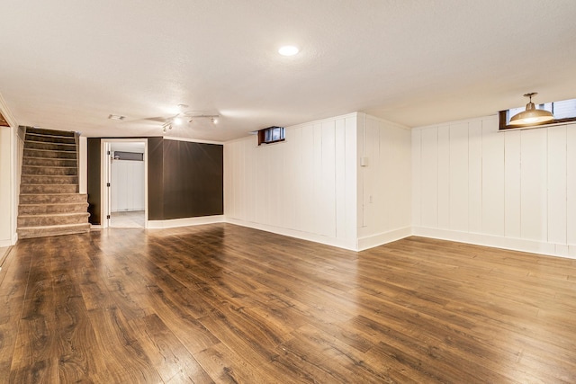 unfurnished living room with wood-type flooring, a textured ceiling, and wood walls