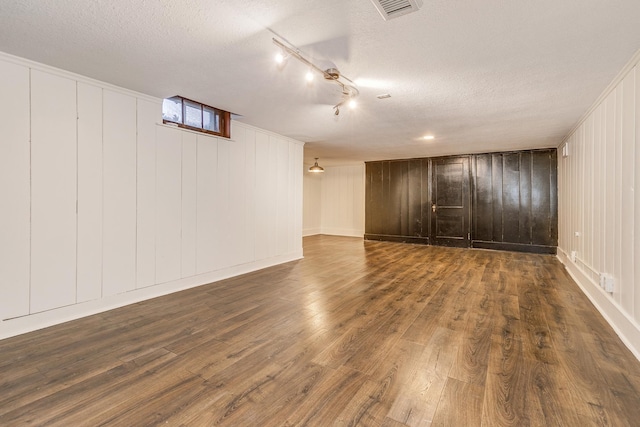 basement featuring dark hardwood / wood-style flooring, a textured ceiling, and wooden walls