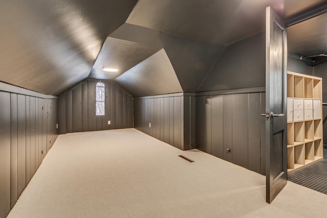 bonus room with wood walls, carpet floors, and vaulted ceiling