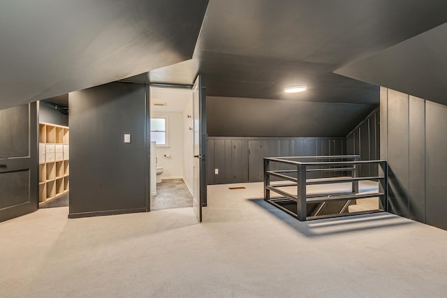 bonus room with wood walls, light carpet, and vaulted ceiling