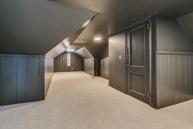 additional living space with carpet, vaulted ceiling, and wooden walls