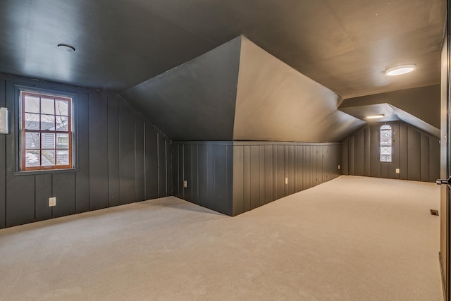 bonus room with carpet, wood walls, and lofted ceiling