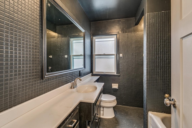 bathroom featuring tile patterned flooring, vanity, toilet, and tile walls