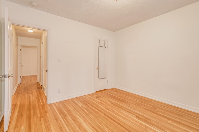 spare room with a textured ceiling and light wood-type flooring