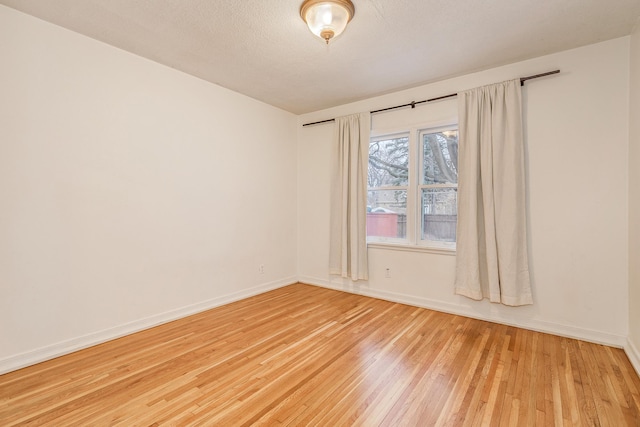 empty room featuring light wood-type flooring and a textured ceiling