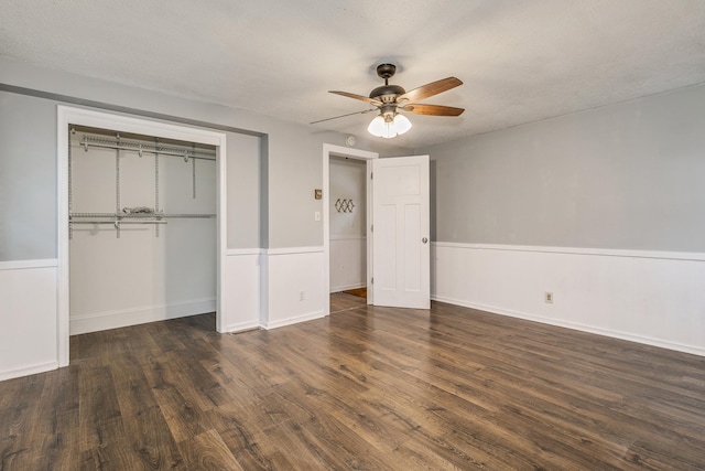 unfurnished bedroom with a textured ceiling, ceiling fan, dark wood-type flooring, and a closet