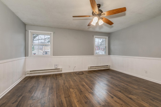 spare room with dark hardwood / wood-style floors, a healthy amount of sunlight, and a baseboard heating unit