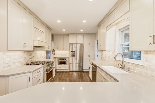 kitchen with premium appliances, backsplash, dark wood-type flooring, and sink