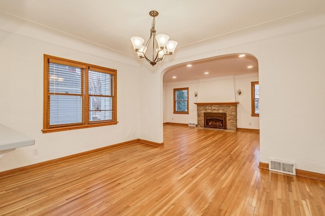 unfurnished living room with a fireplace, light hardwood / wood-style floors, and a notable chandelier