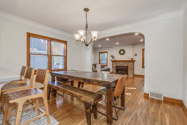 dining space featuring hardwood / wood-style floors, a notable chandelier, and a fireplace