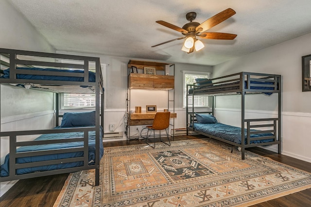 bedroom featuring ceiling fan, a baseboard radiator, dark hardwood / wood-style floors, and a textured ceiling