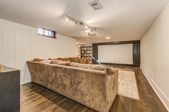 home theater with dark hardwood / wood-style floors and track lighting