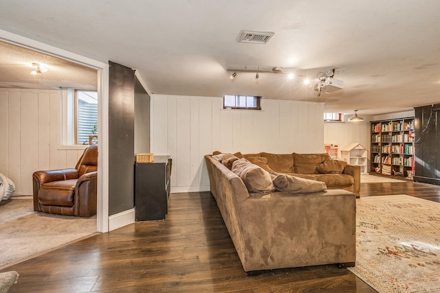 living room featuring wooden walls, rail lighting, and dark hardwood / wood-style floors