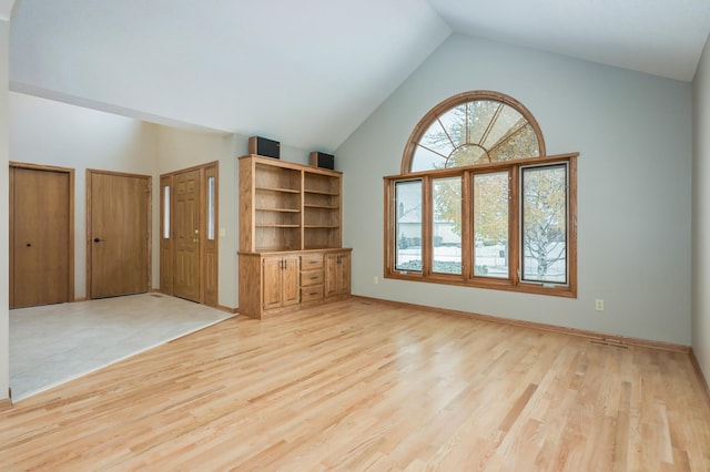 unfurnished living room with light wood-type flooring and vaulted ceiling