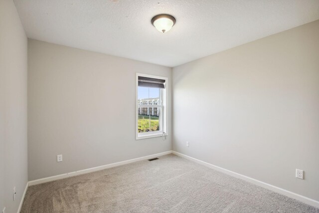 carpeted spare room featuring a textured ceiling