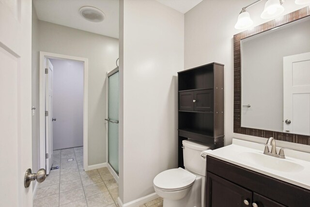 bathroom with a shower with door, vanity, toilet, and tile patterned floors