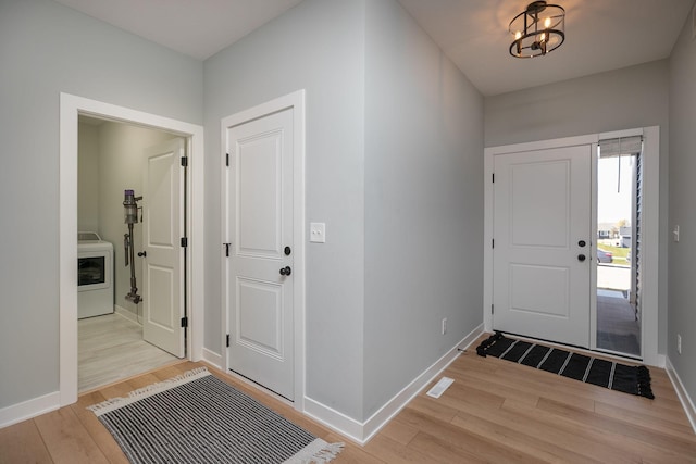 entrance foyer with a notable chandelier, washer / clothes dryer, and light hardwood / wood-style flooring