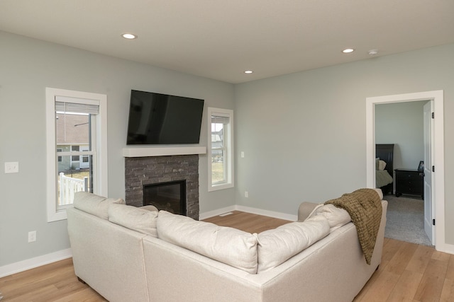 living room with a stone fireplace and light hardwood / wood-style flooring