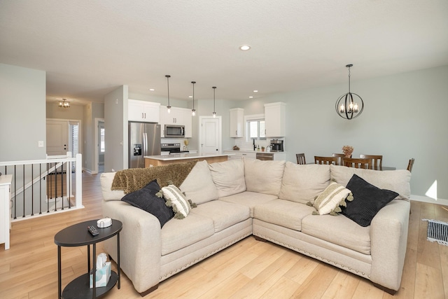 living room featuring a notable chandelier and light wood-type flooring