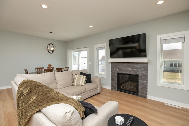 living room featuring light hardwood / wood-style flooring, a fireplace, and an inviting chandelier