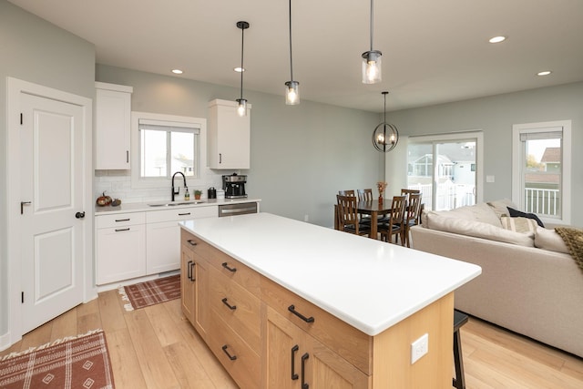 kitchen with sink, plenty of natural light, a kitchen island, and white cabinets