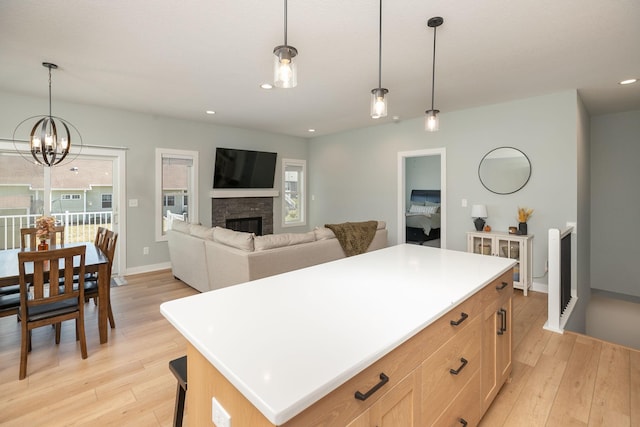 kitchen featuring light brown cabinets, a center island, pendant lighting, an inviting chandelier, and light wood-type flooring