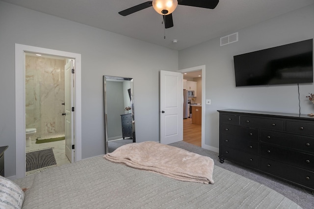 carpeted bedroom with ensuite bath and ceiling fan