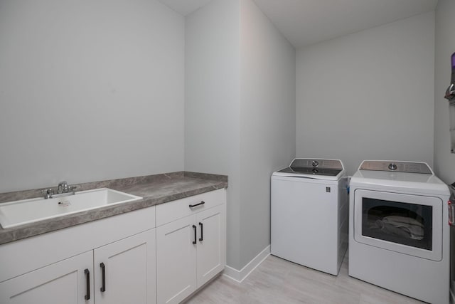 laundry room with light hardwood / wood-style flooring, washing machine and dryer, sink, and cabinets