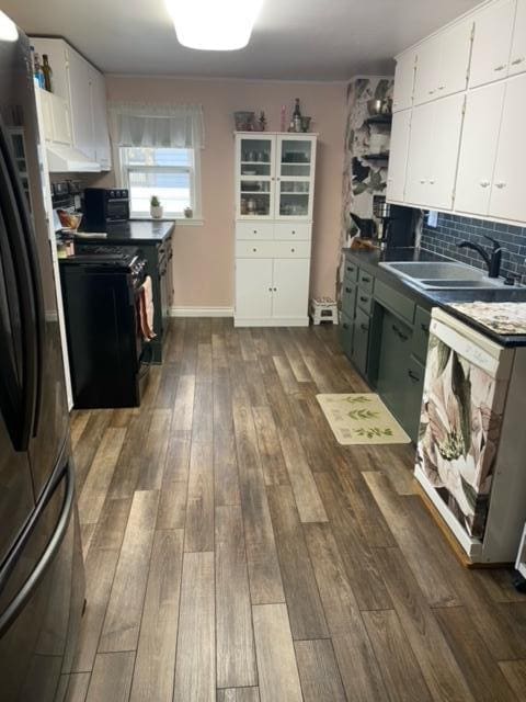 kitchen with dark hardwood / wood-style flooring, sink, dishwasher, white cabinets, and stainless steel refrigerator