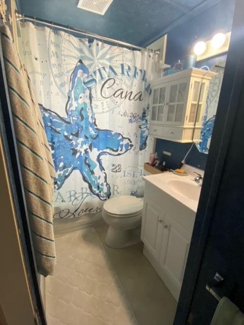 bathroom featuring tile patterned flooring, vanity, toilet, and walk in shower