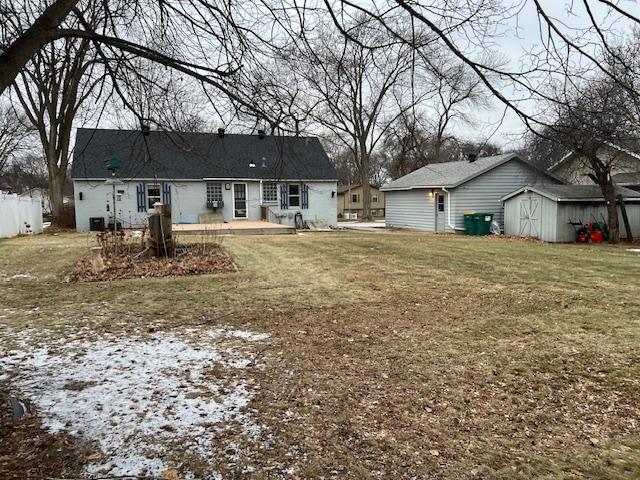 back of house with a storage shed and a lawn