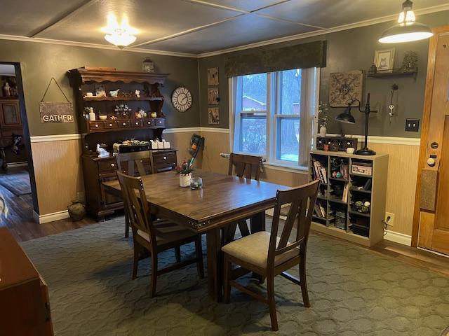 dining area with hardwood / wood-style floors, ornamental molding, and wood walls