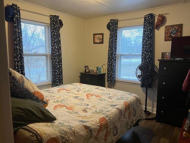 bedroom featuring multiple windows, wood-type flooring, and ornamental molding