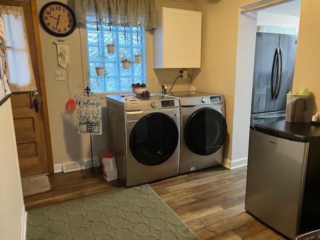 laundry area with separate washer and dryer, crown molding, cabinets, and light wood-type flooring