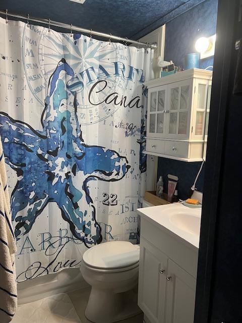 bathroom with a shower with shower curtain, a textured ceiling, vanity, and toilet