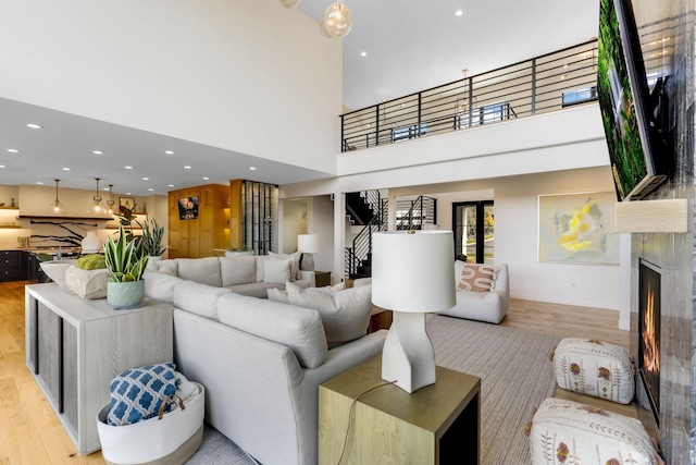 living room with light hardwood / wood-style floors, a high end fireplace, and a towering ceiling