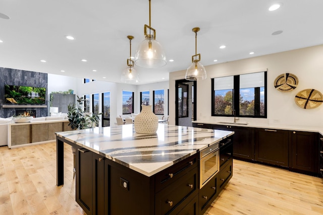 kitchen featuring decorative light fixtures, light hardwood / wood-style flooring, a center island, and sink