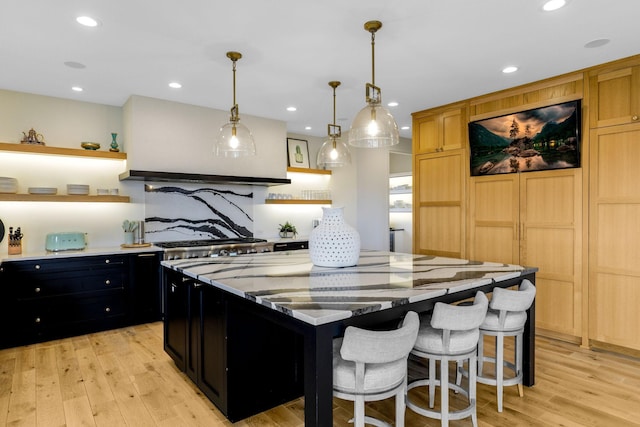 kitchen featuring a center island, decorative light fixtures, tasteful backsplash, light hardwood / wood-style floors, and a breakfast bar area