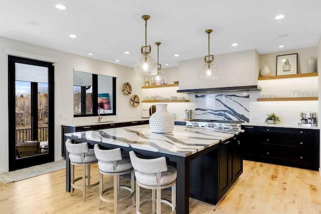 kitchen featuring light hardwood / wood-style floors, a breakfast bar area, sink, hanging light fixtures, and a center island