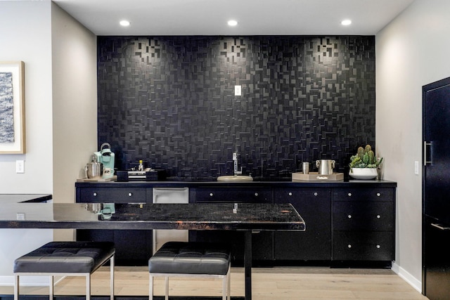 bar with decorative backsplash and light wood-type flooring