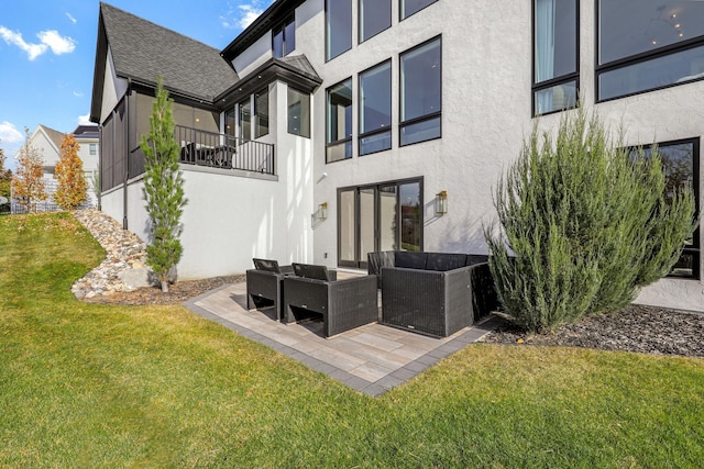 rear view of property with an outdoor living space, a lawn, and a patio