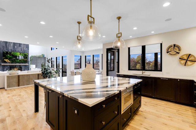 kitchen with light wood-type flooring, sink, pendant lighting, and a center island