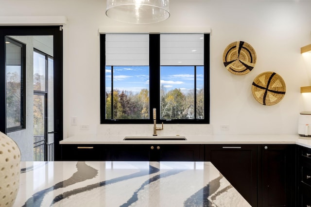 kitchen featuring light stone counters and sink