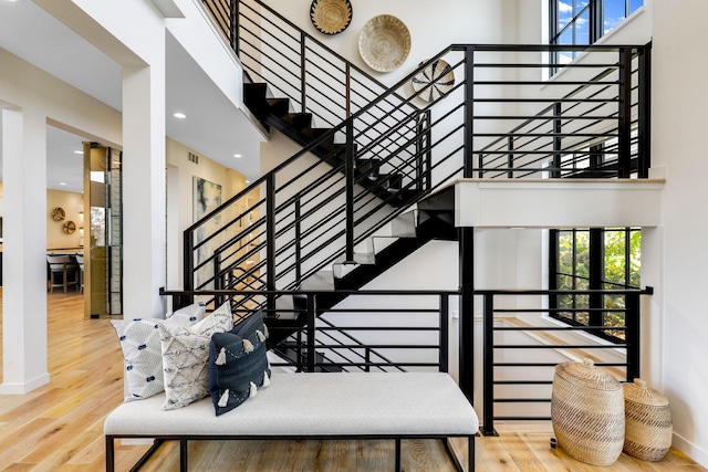 staircase with a towering ceiling and hardwood / wood-style floors