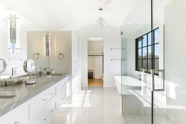 bathroom with a tub, vanity, and vaulted ceiling