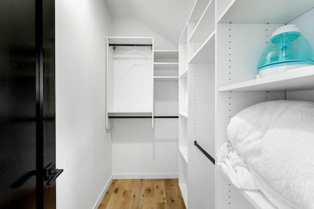 walk in closet with light hardwood / wood-style floors and vaulted ceiling